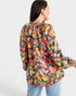 Woman wearing a colorful patterned blouse against a white background
