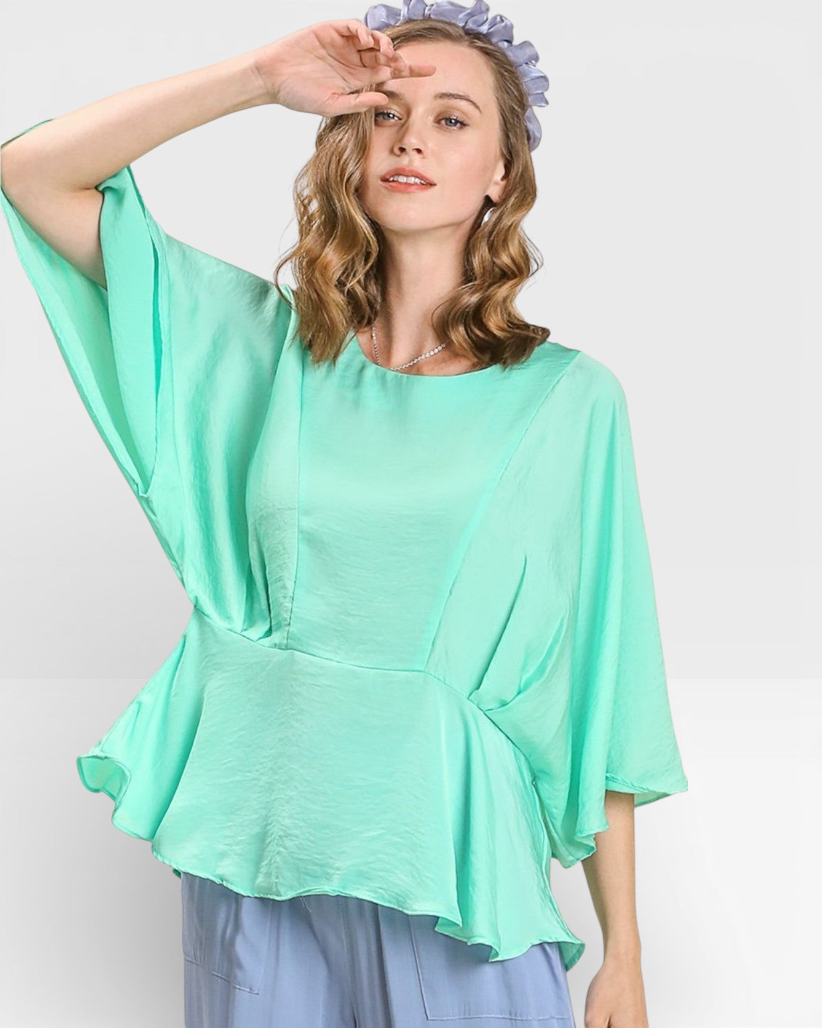 Woman wearing a light green blouse with a plain background