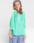 Woman wearing a light green top and blue pants on a white background