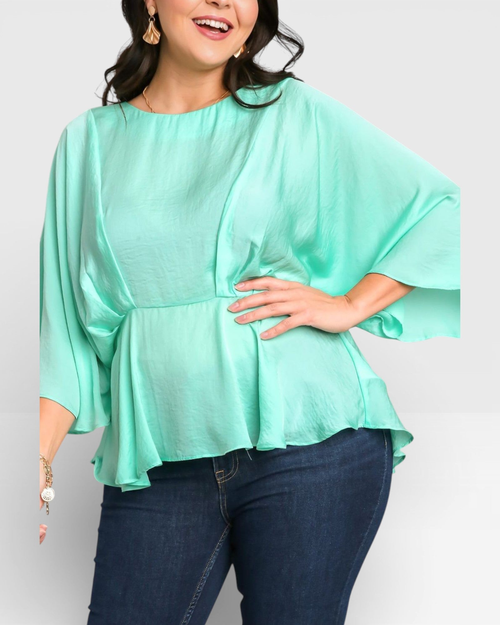 Woman wearing a light green blouse and dark blue jeans on a white background