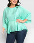 Woman wearing a light green blouse and dark blue jeans on a white background