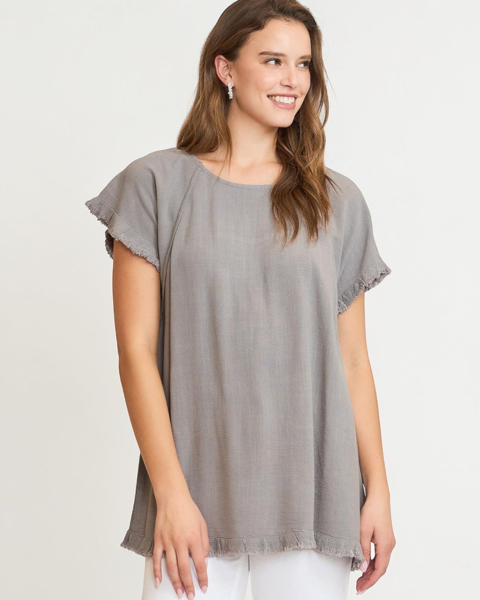 Woman wearing a gray tunic with ruffled sleeves on a white background