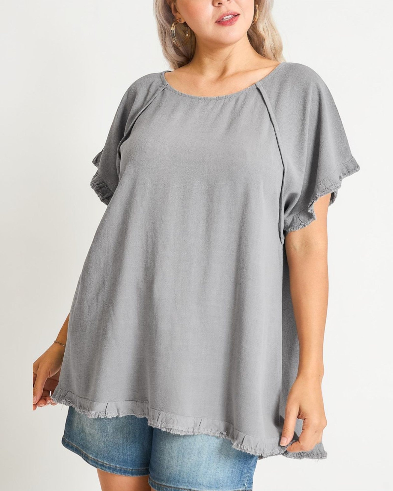 Woman wearing a gray blouse with short sleeves on a plain background