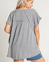 Woman wearing a gray tunic with denim shorts on a plain background