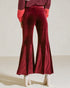 Red velvet flared pants worn by a person on a plain background