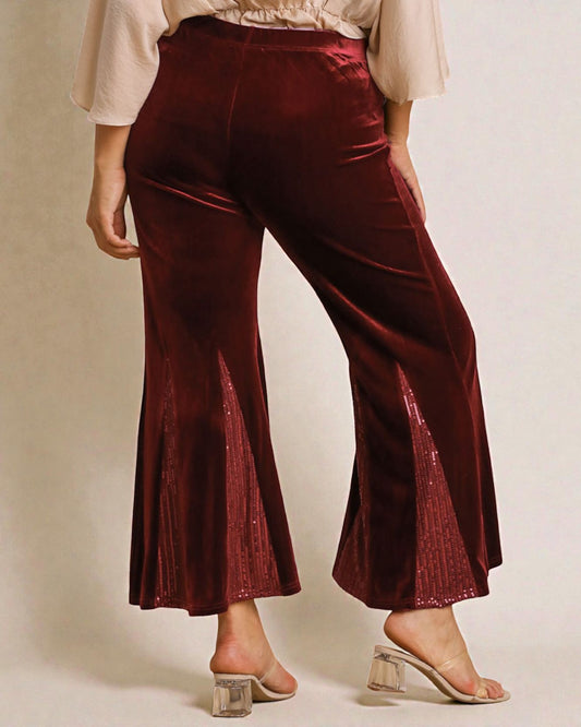 Maroon velvet pants worn by a person on a neutral background
