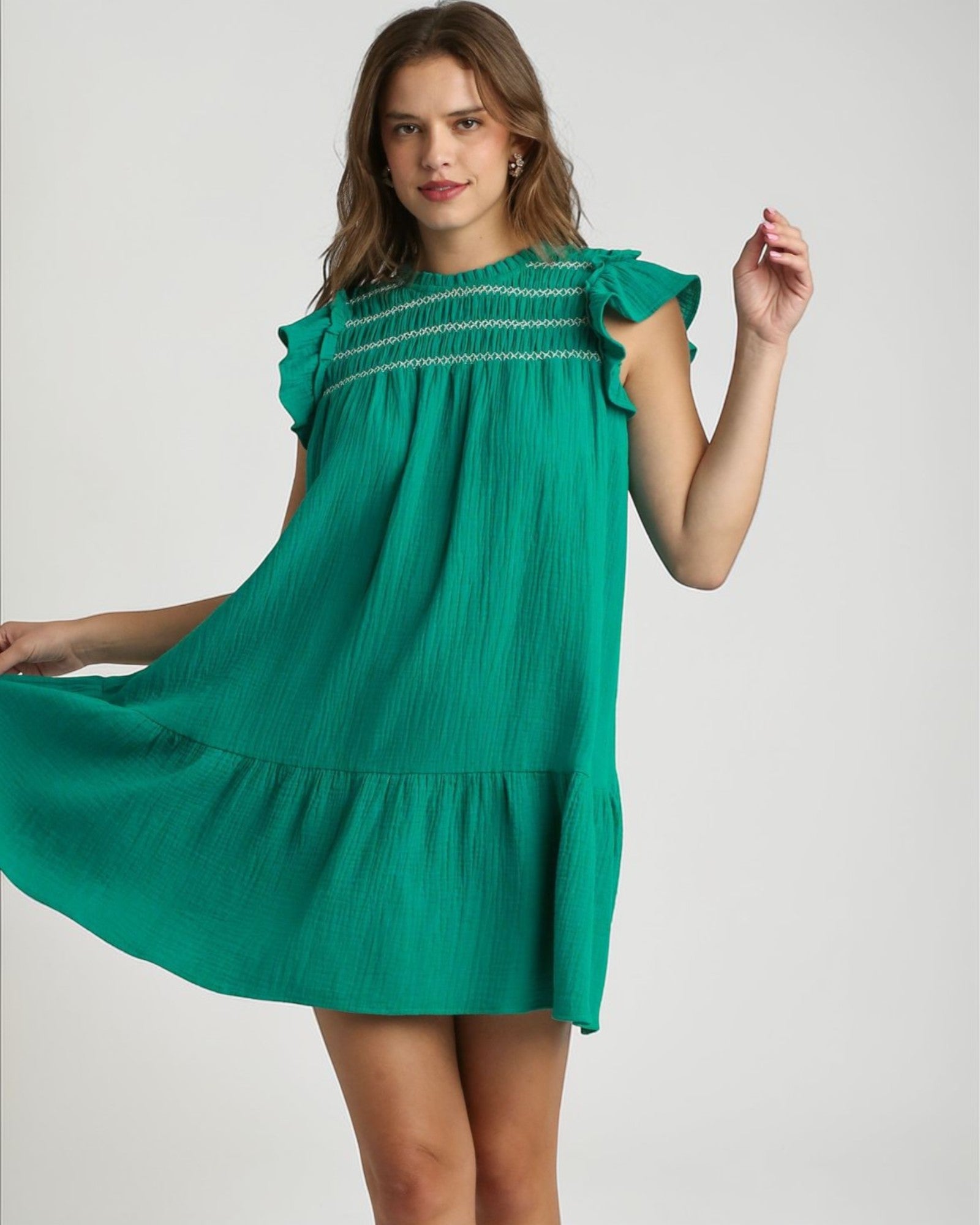 Woman wearing a green dress with ruffled sleeves on a white background