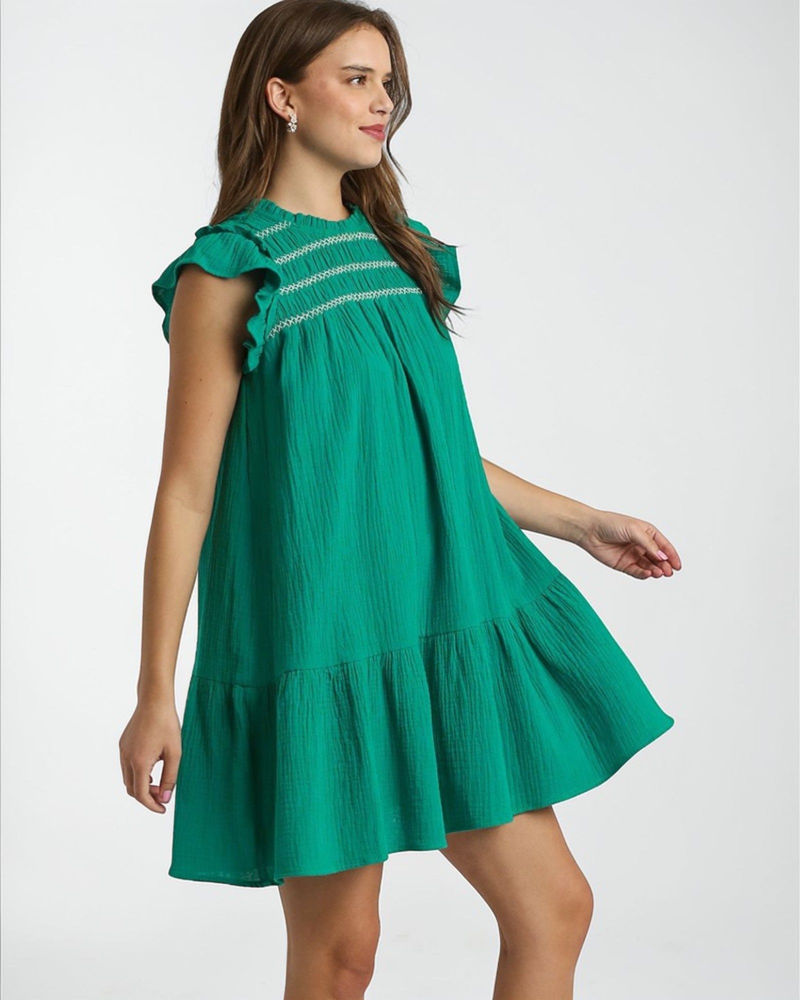 Woman wearing a green dress with smocked bodice on a white background