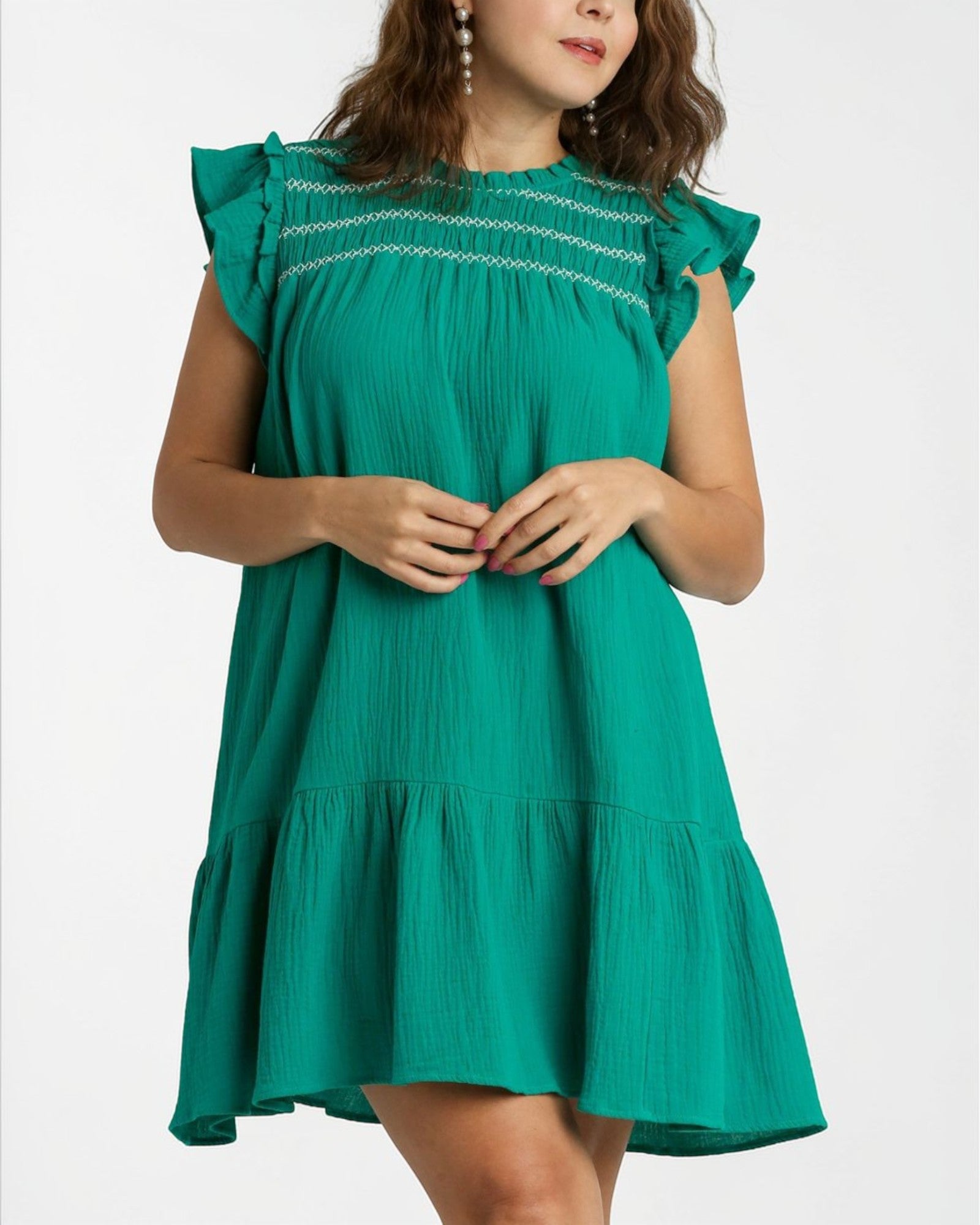 Woman wearing a green dress with ruffled sleeves on a white background