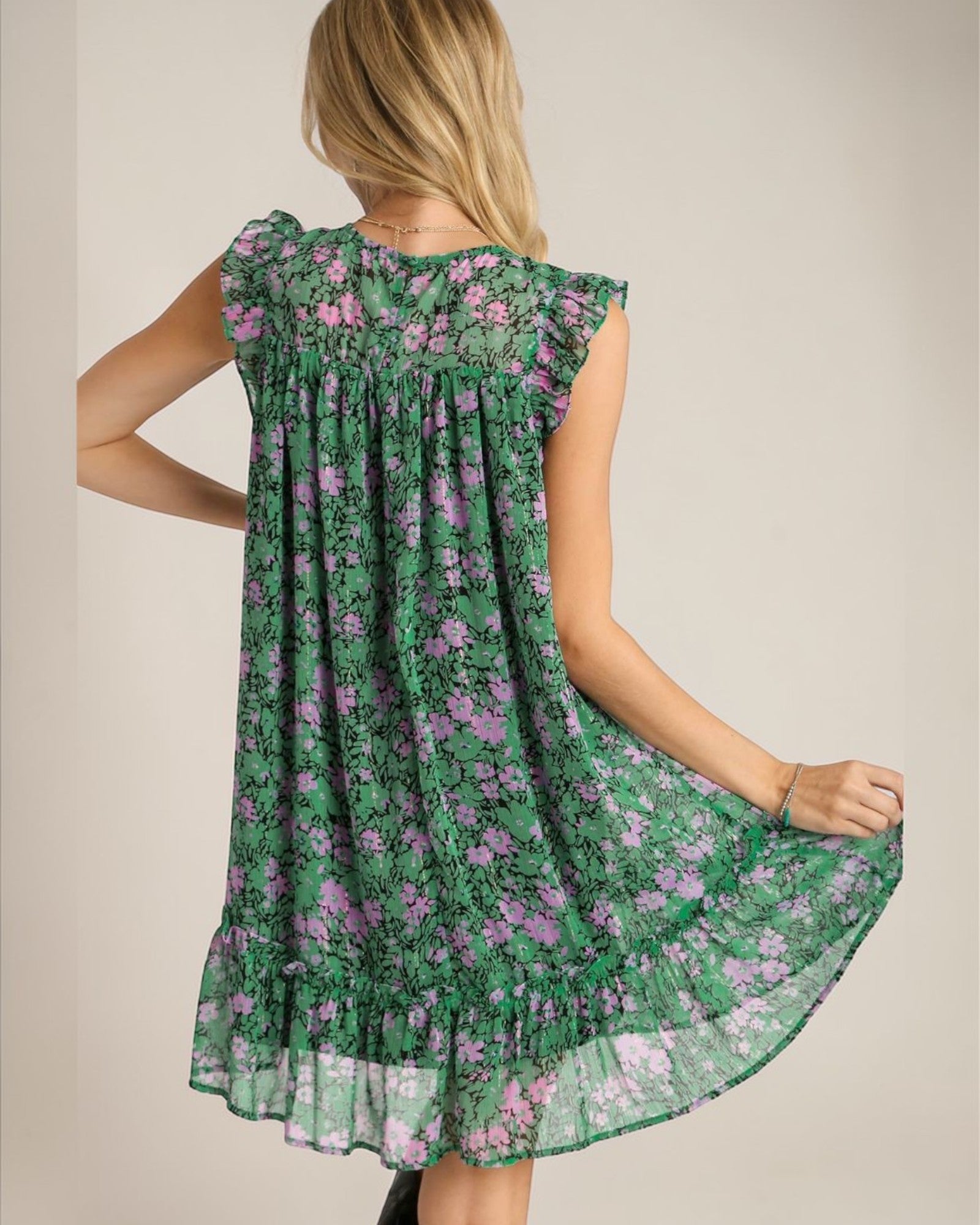 Woman wearing a green floral dress against a plain background