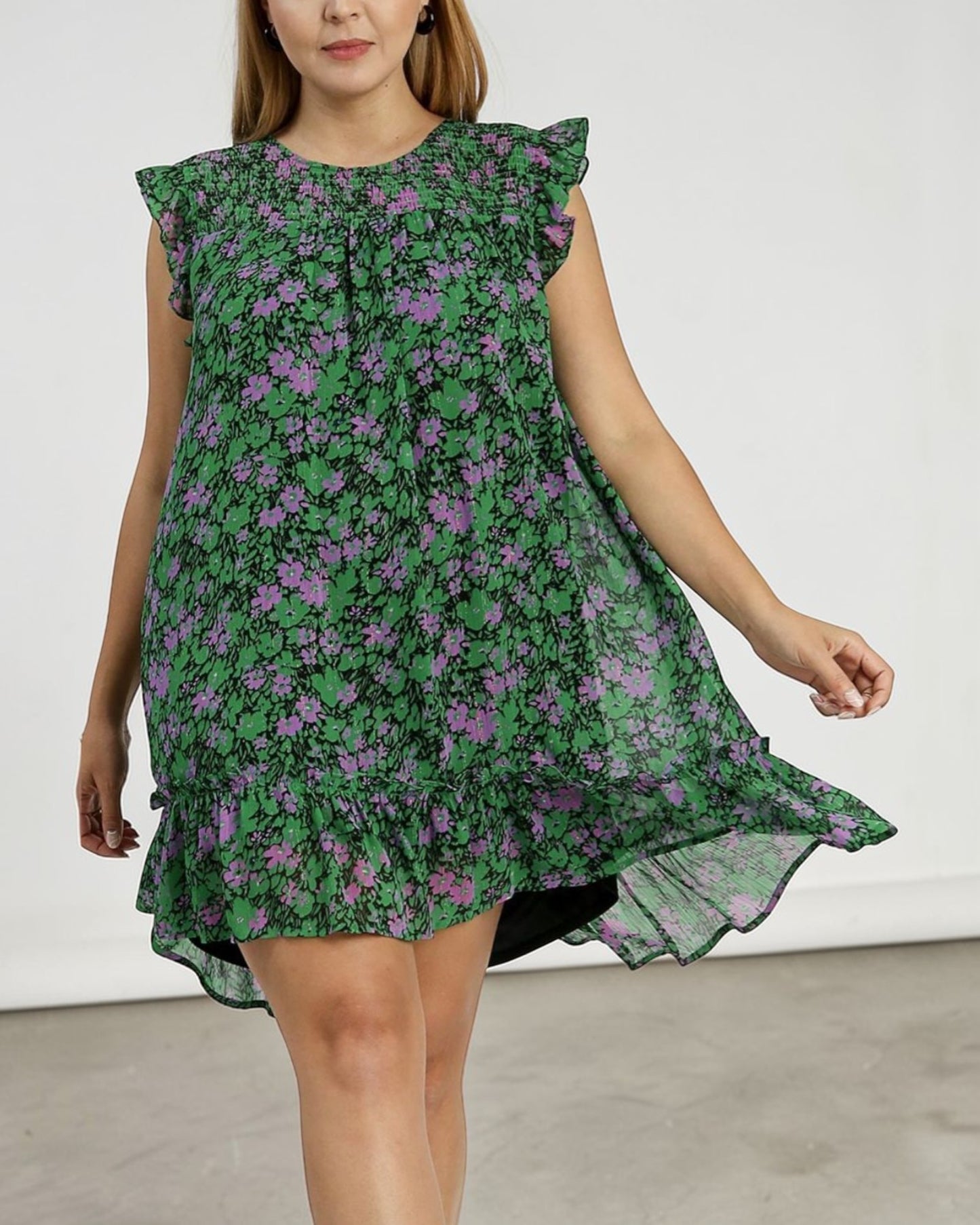 Woman wearing a green floral dress with purple flowers on a white background