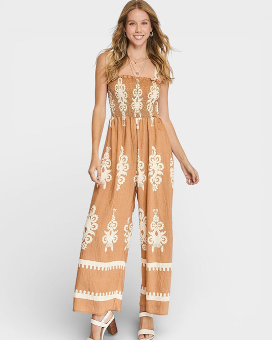Woman wearing a brown jumpsuit with white lace details on a white background