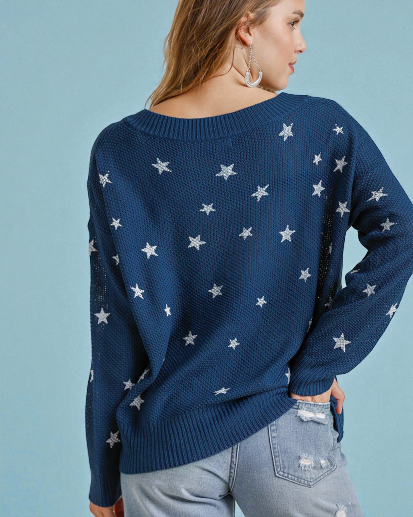 Person wearing a navy blue sweater with star patterns on a light blue background