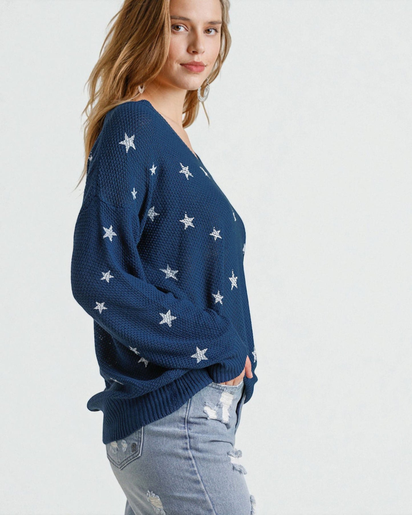 Woman wearing a navy blue sweater with star patterns on a white background