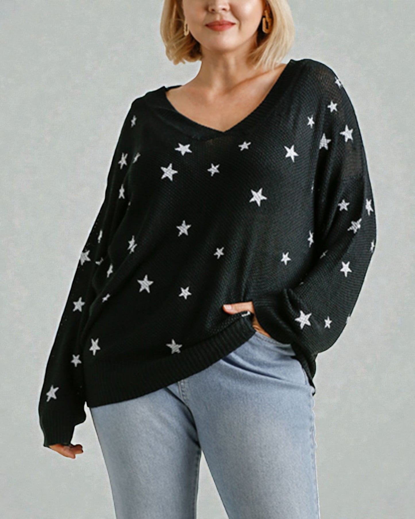 Person wearing a black sweater with white star patterns on a plain background