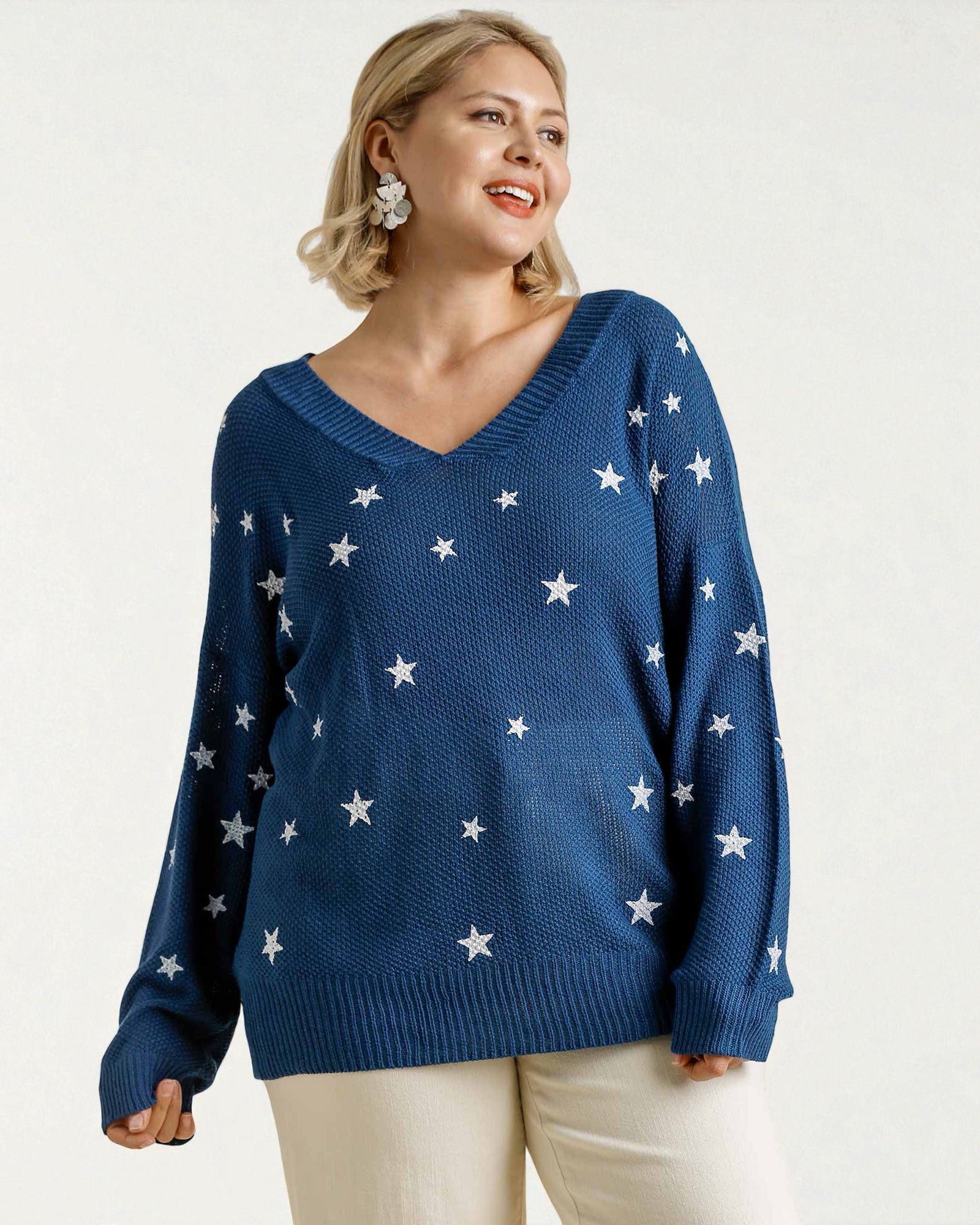 Woman wearing a blue sweater with white star patterns on a plain background