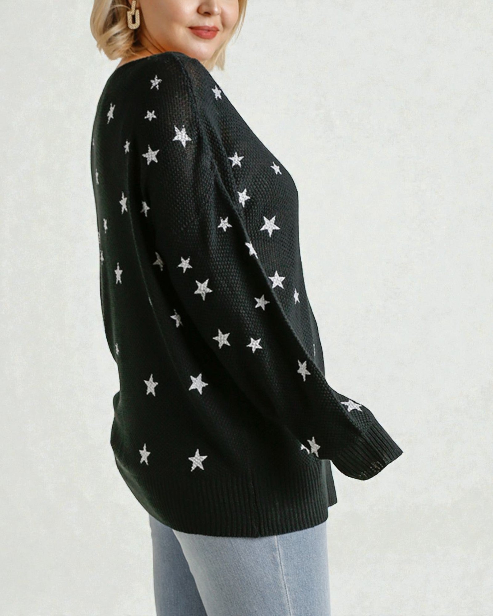 Black sweater with white star patterns worn by a person on a light gray background