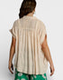 Woman wearing a beige sleeveless top with a plain background