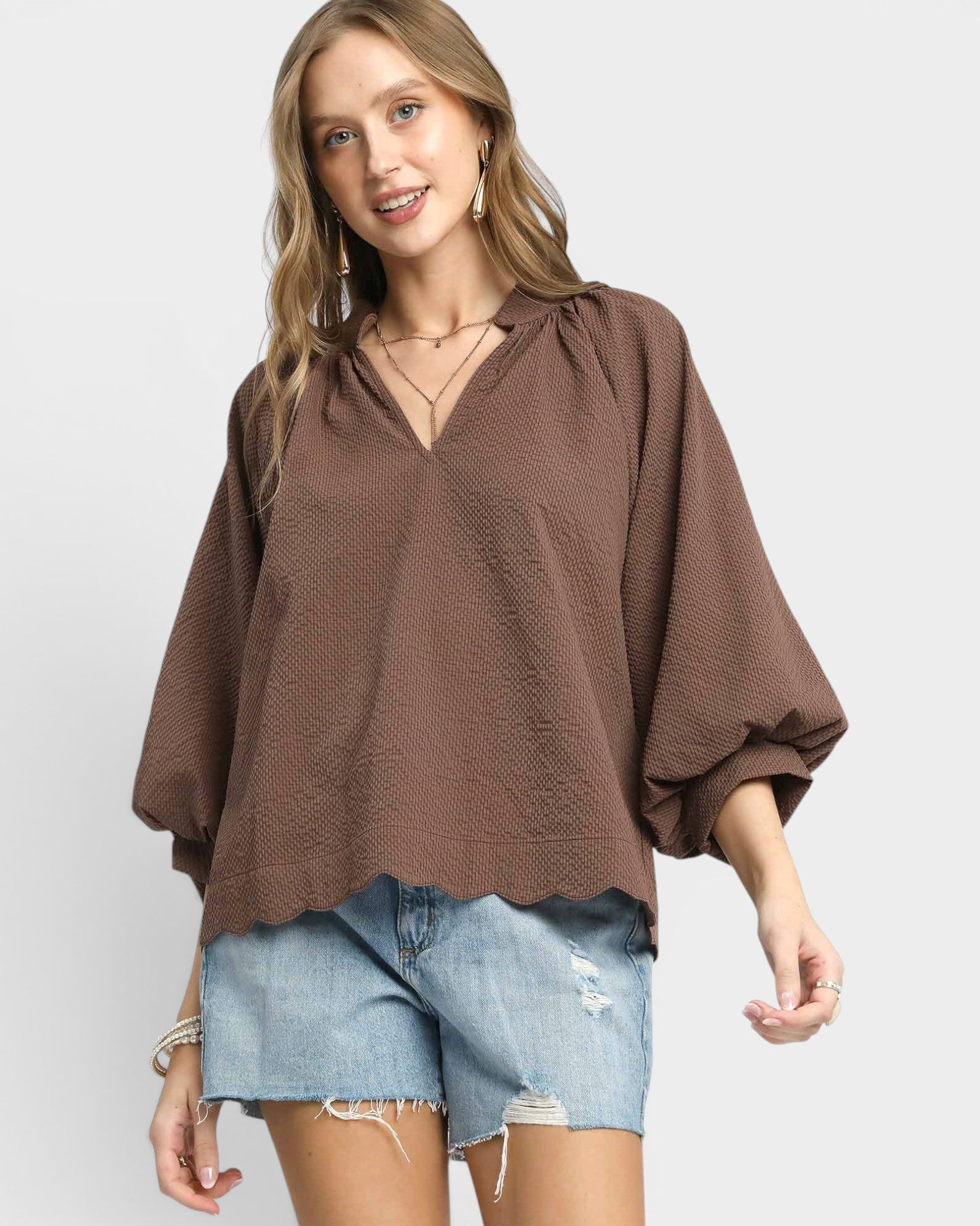 Woman wearing a brown blouse and denim shorts on a white background