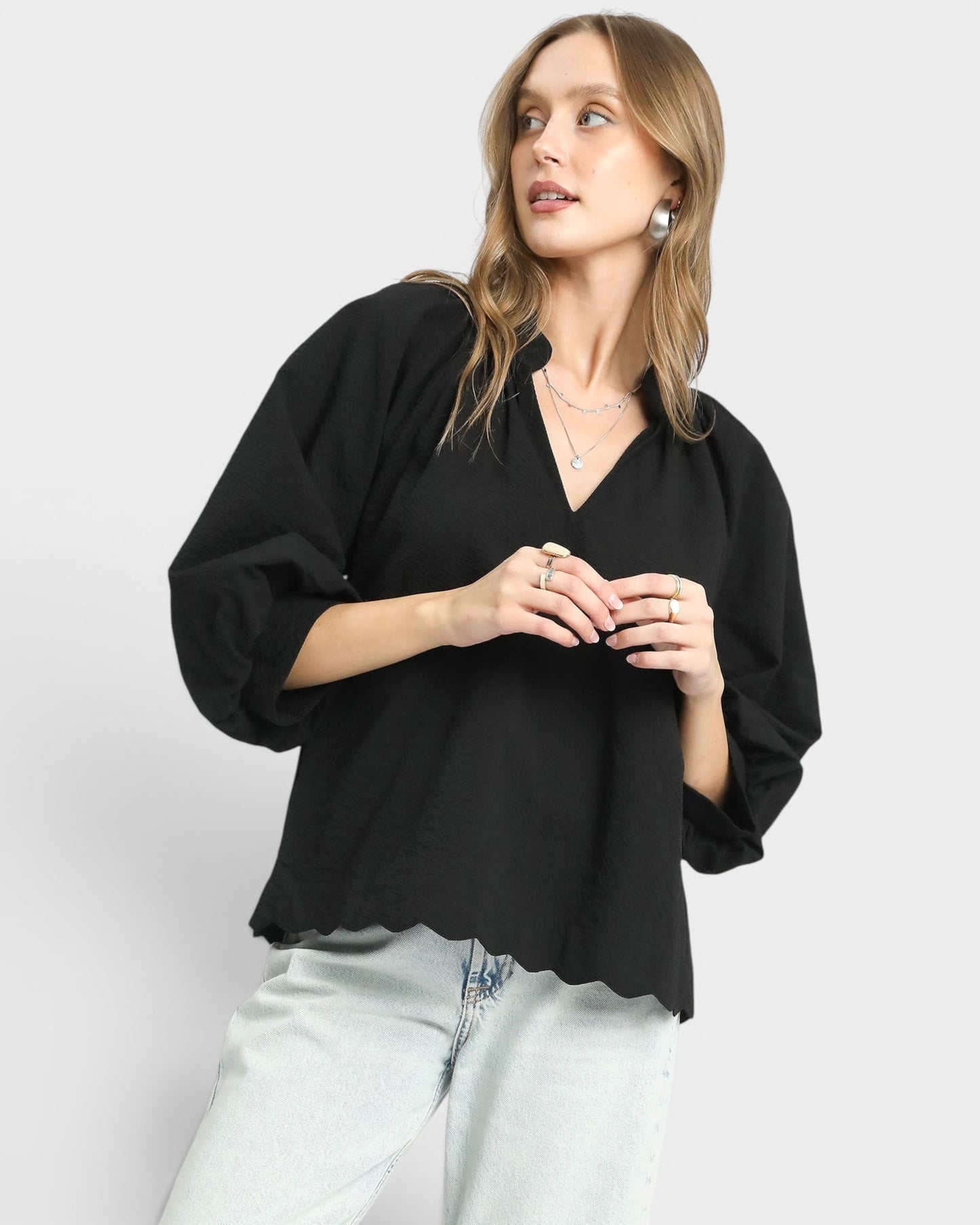 Woman wearing a black blouse and light blue jeans on a white background
