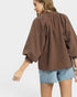 Woman wearing a brown blouse and denim shorts on a white background