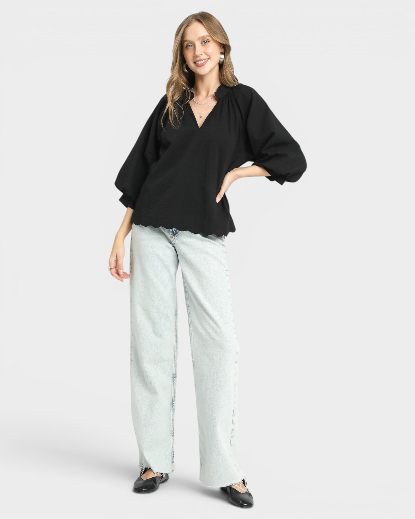 Woman wearing a black top and light blue pants on a white background