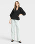 Woman wearing a black top and light blue pants on a white background