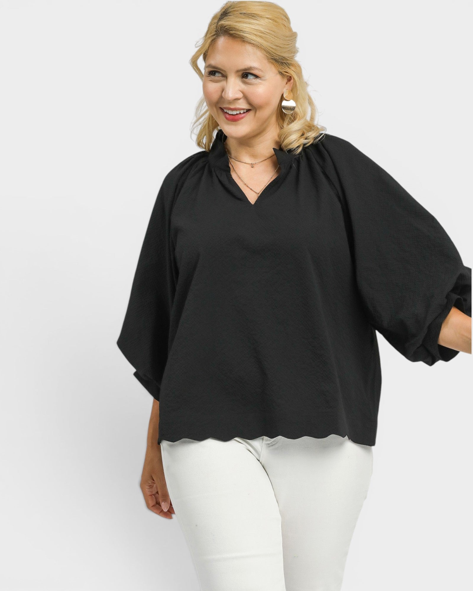 Woman wearing a black blouse and white pants on a white background
