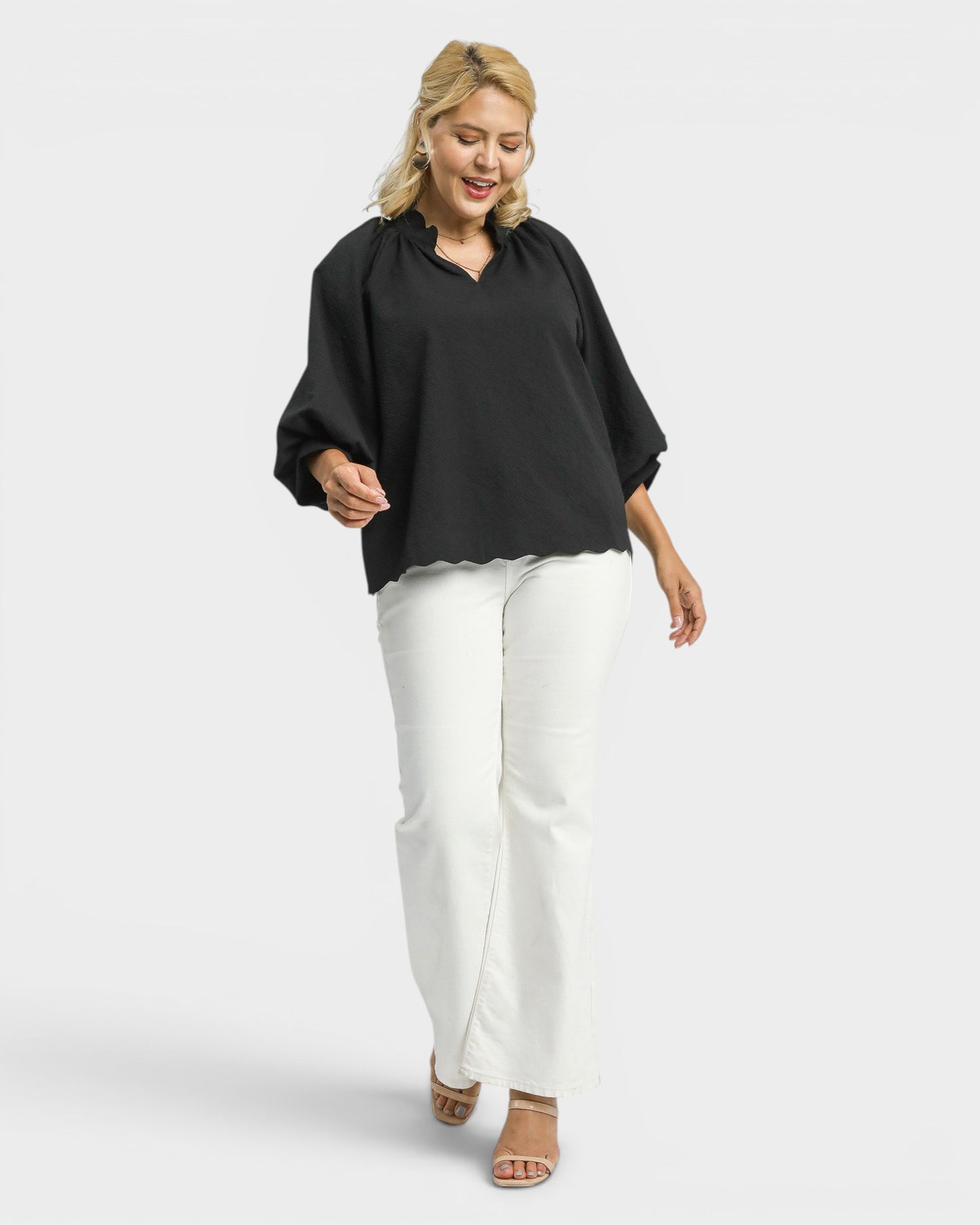 Woman wearing a black top and white pants on a white background