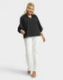 Woman wearing a black top and white pants on a white background
