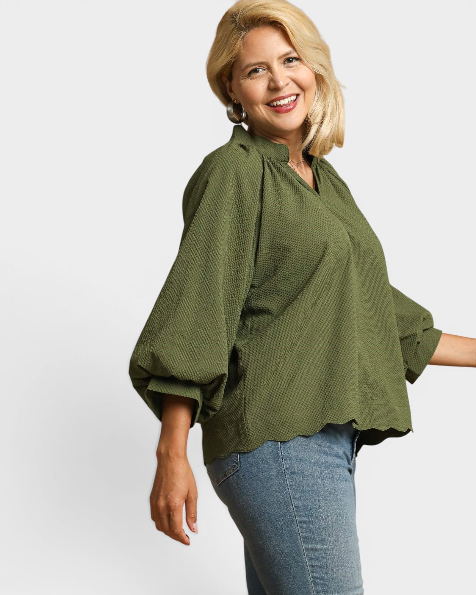 Woman wearing a green blouse and blue jeans on a white background