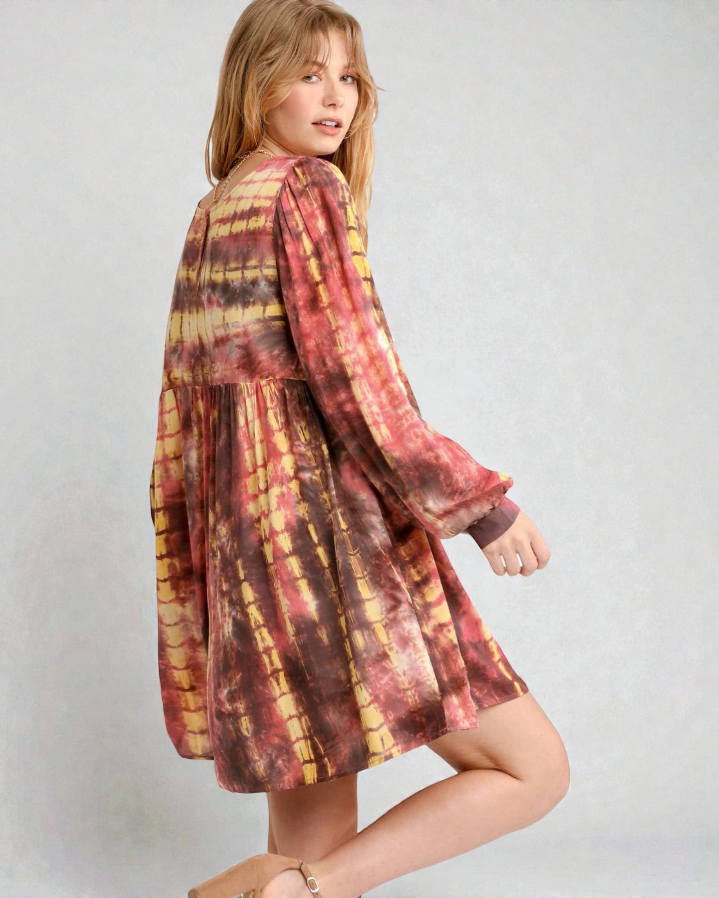 Woman wearing a tie-dye dress on a plain background