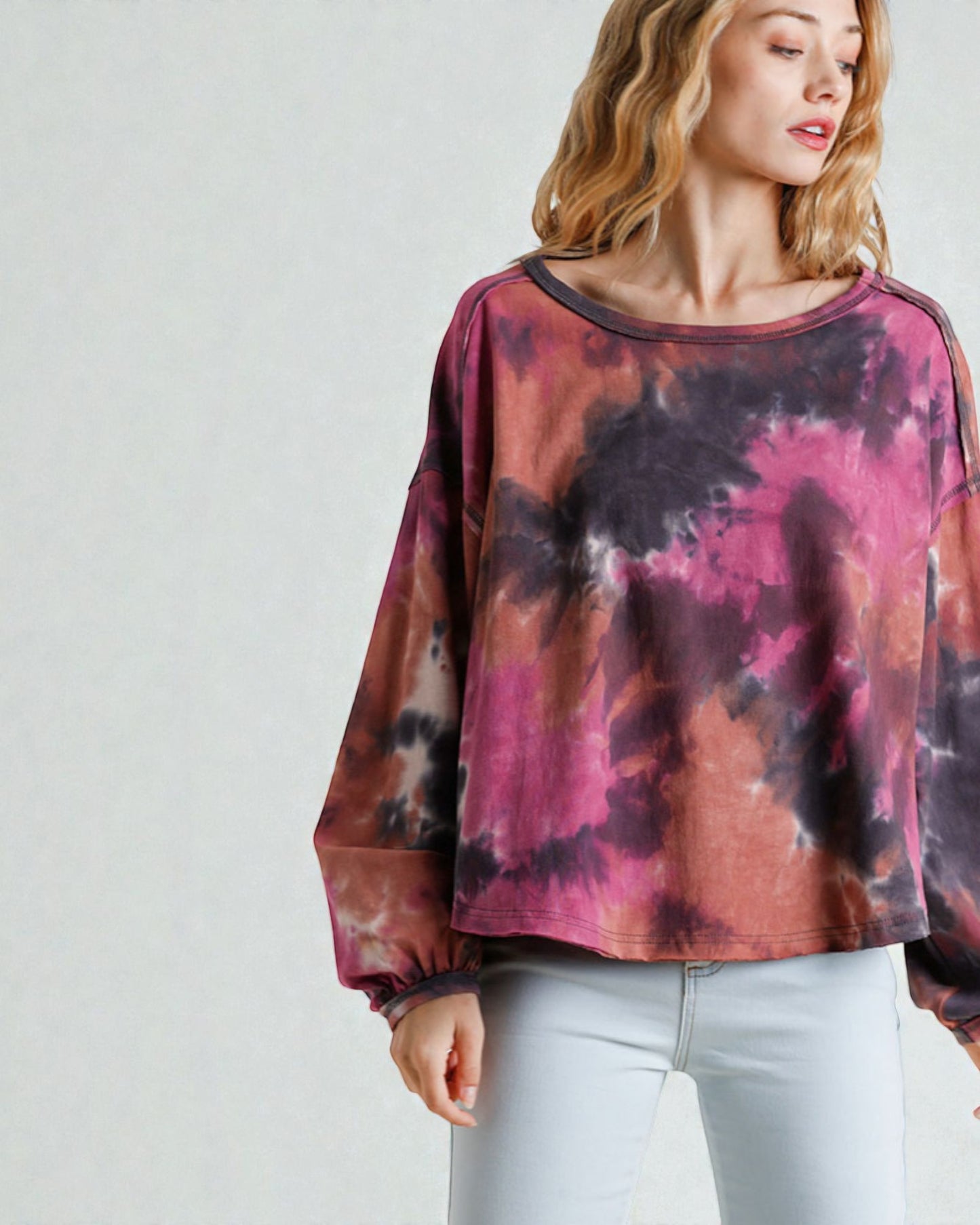 Woman wearing a tie-dye long-sleeve top with a plain background