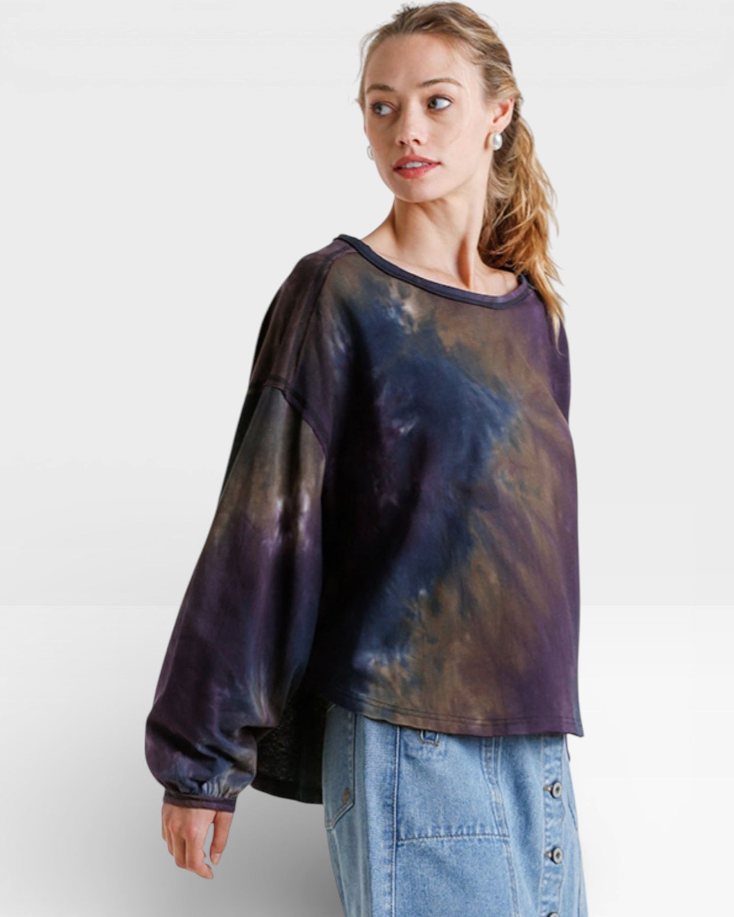 Woman wearing a tie-dye shirt and jeans on a white background