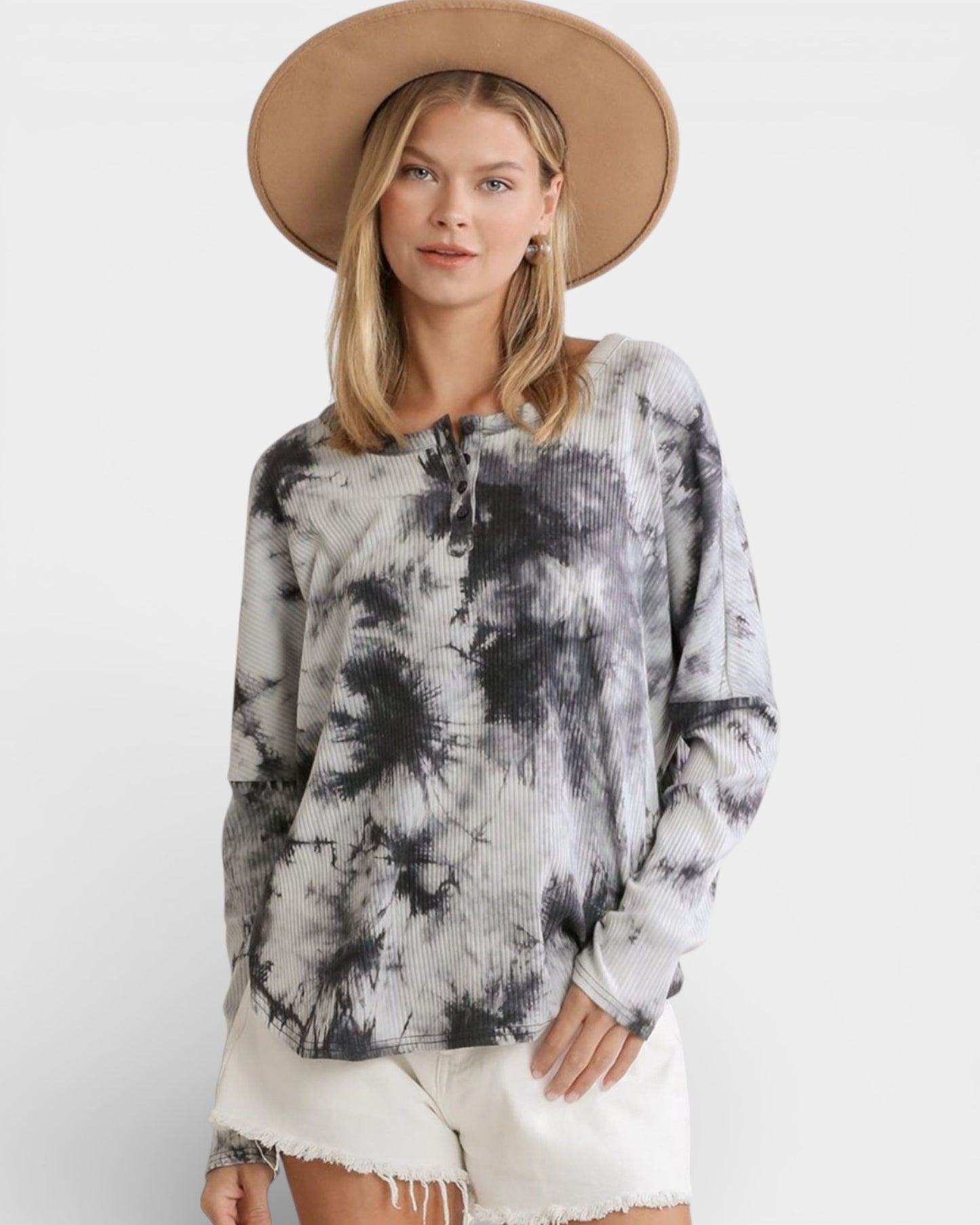 Woman wearing a tie-dye top and beige hat on a white background