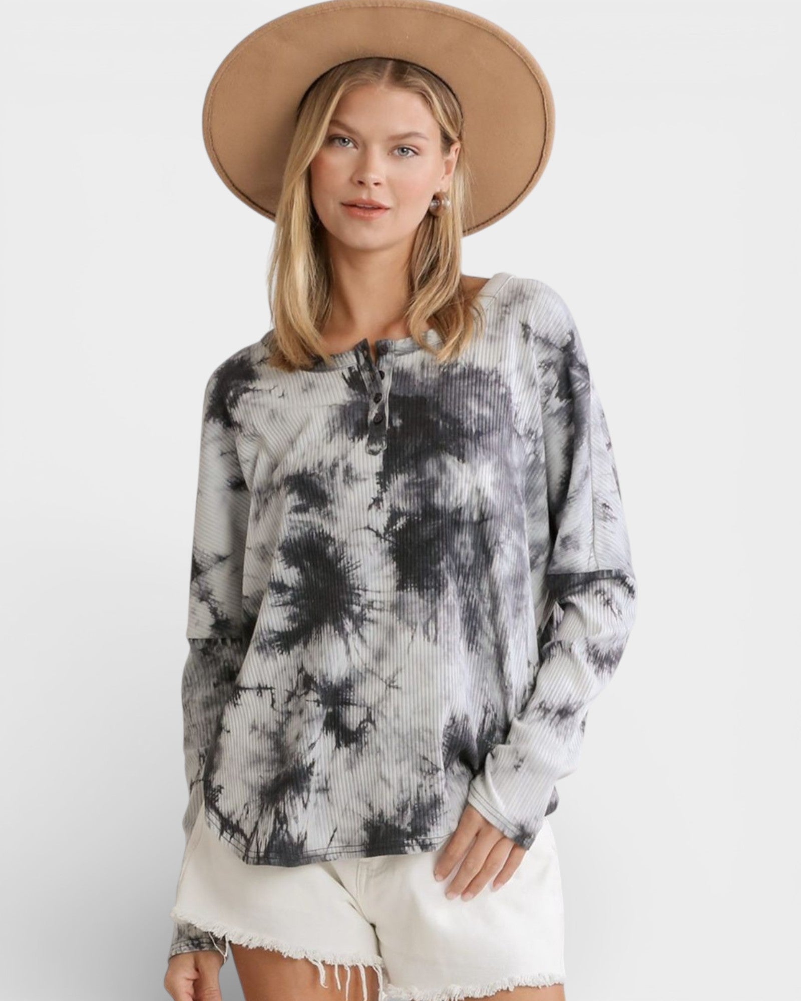 Woman wearing a tie-dye top and beige hat on a white background