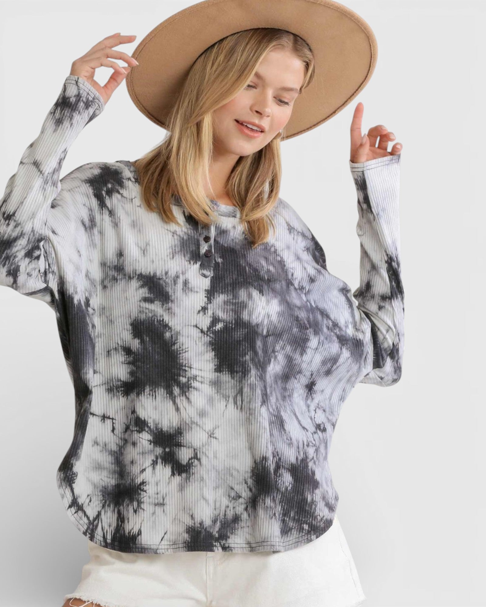 Woman wearing a tie-dye sweater and beige hat on a white background