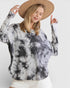 Woman wearing a tie-dye sweater and beige hat on a white background