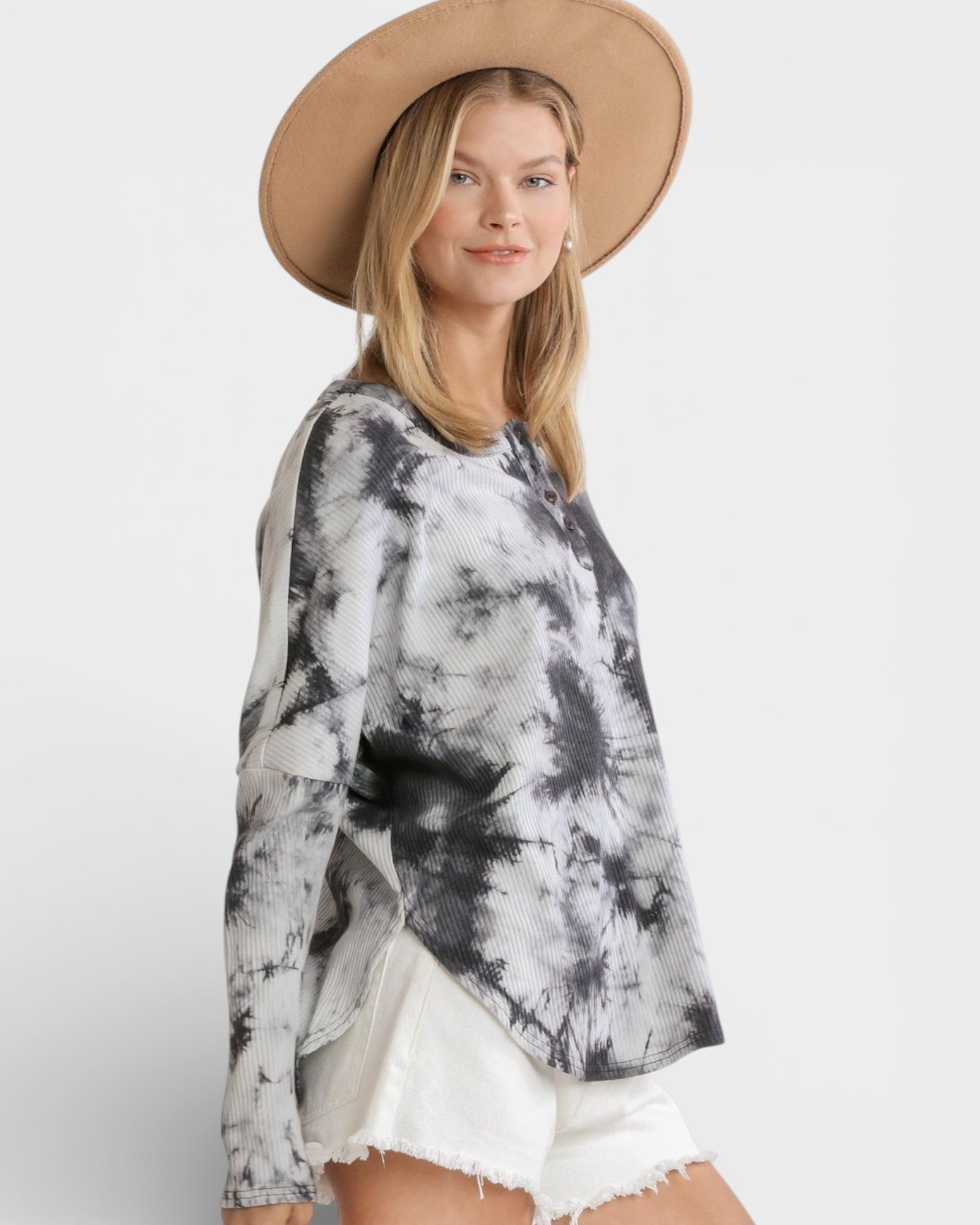 Woman wearing a tie-dye shirt and beige hat on a white background