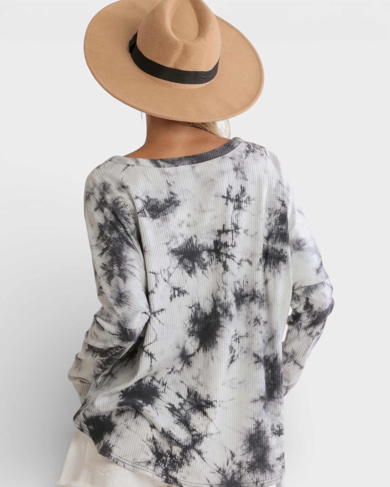 Person wearing a tie-dye long-sleeve shirt and a beige hat on a white background