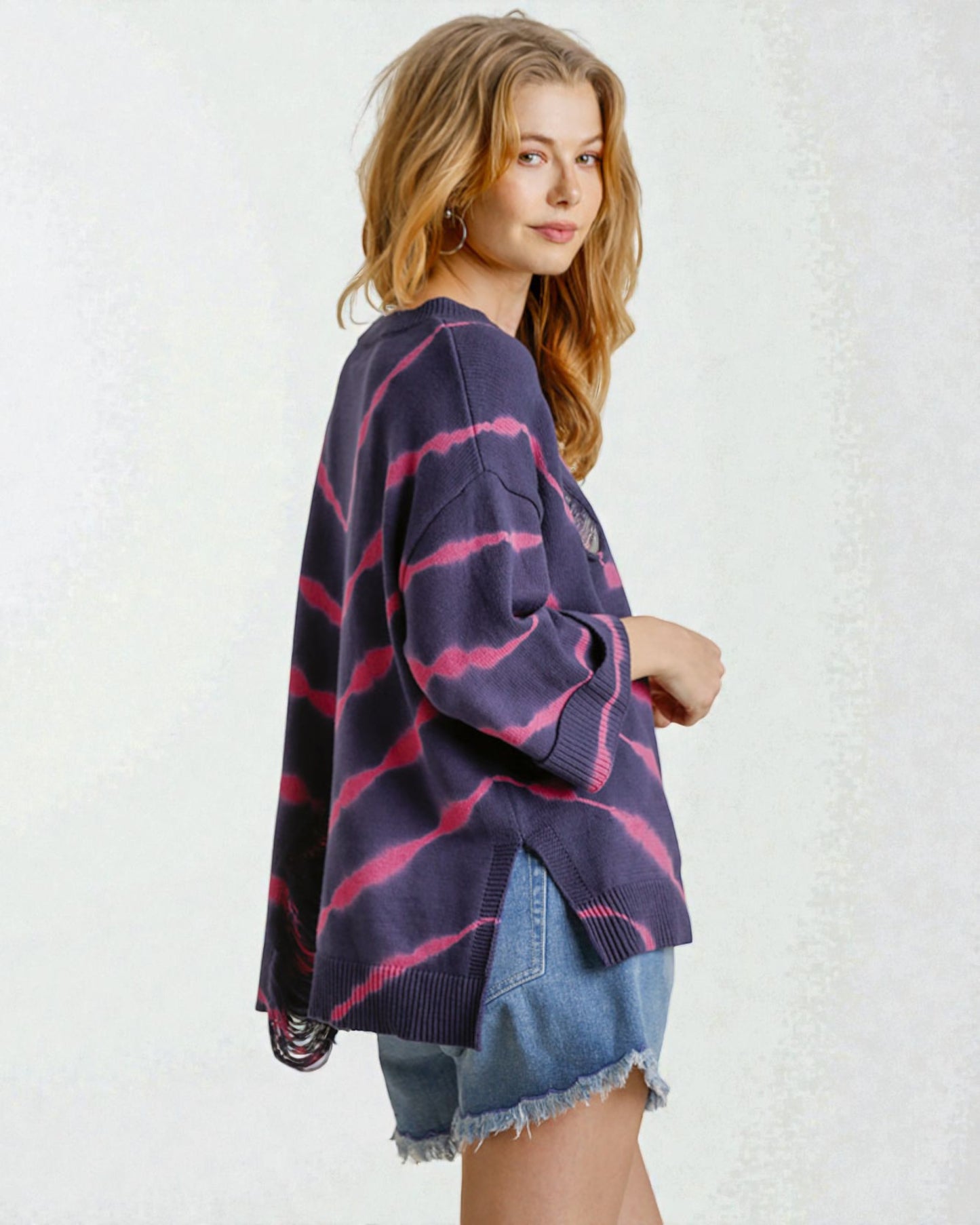 Woman wearing a purple and pink striped sweater over a denim shirt on a white background