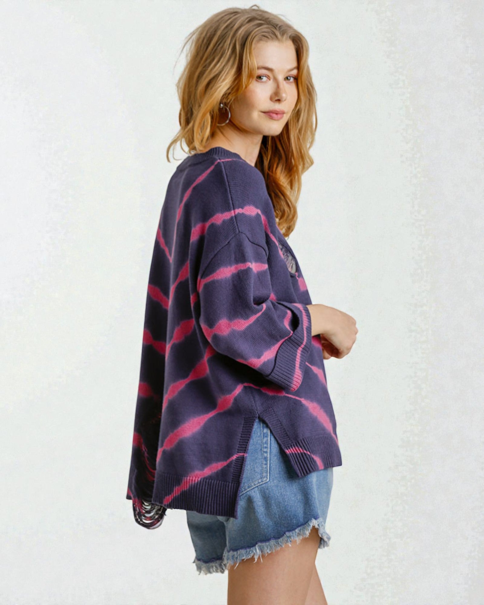 Woman wearing a purple and pink striped sweater over a denim shirt on a white background
