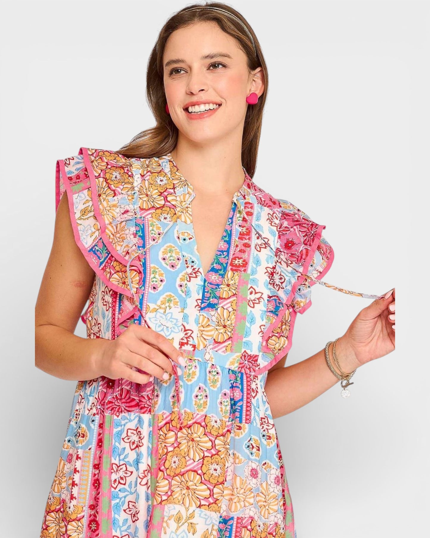 Woman wearing a colorful floral dress with ruffled sleeves on a white background