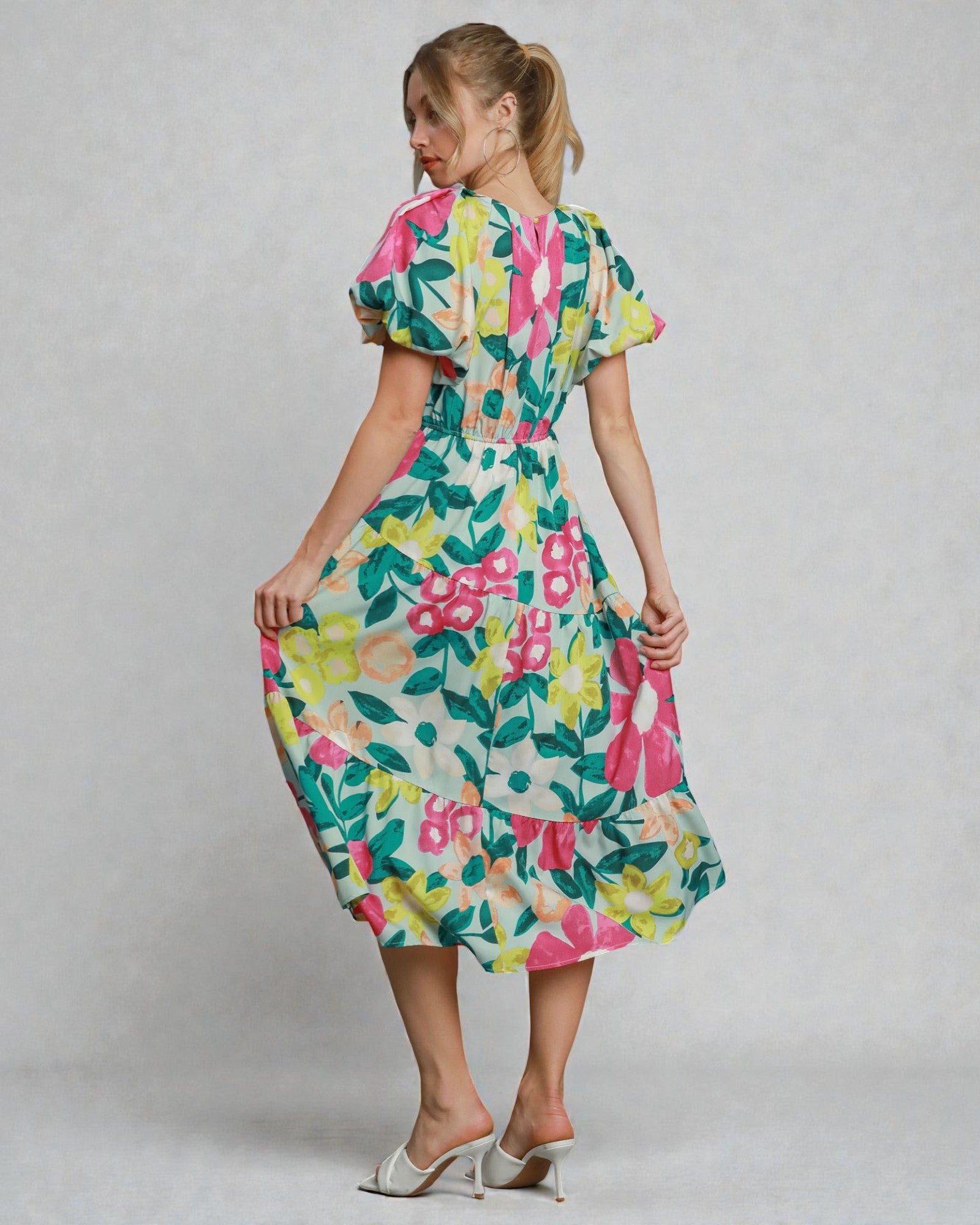 Woman wearing a colorful floral dress against a plain background