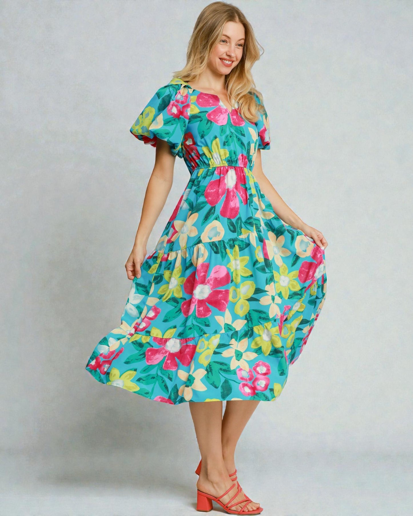 Woman wearing a colorful floral dress against a plain background