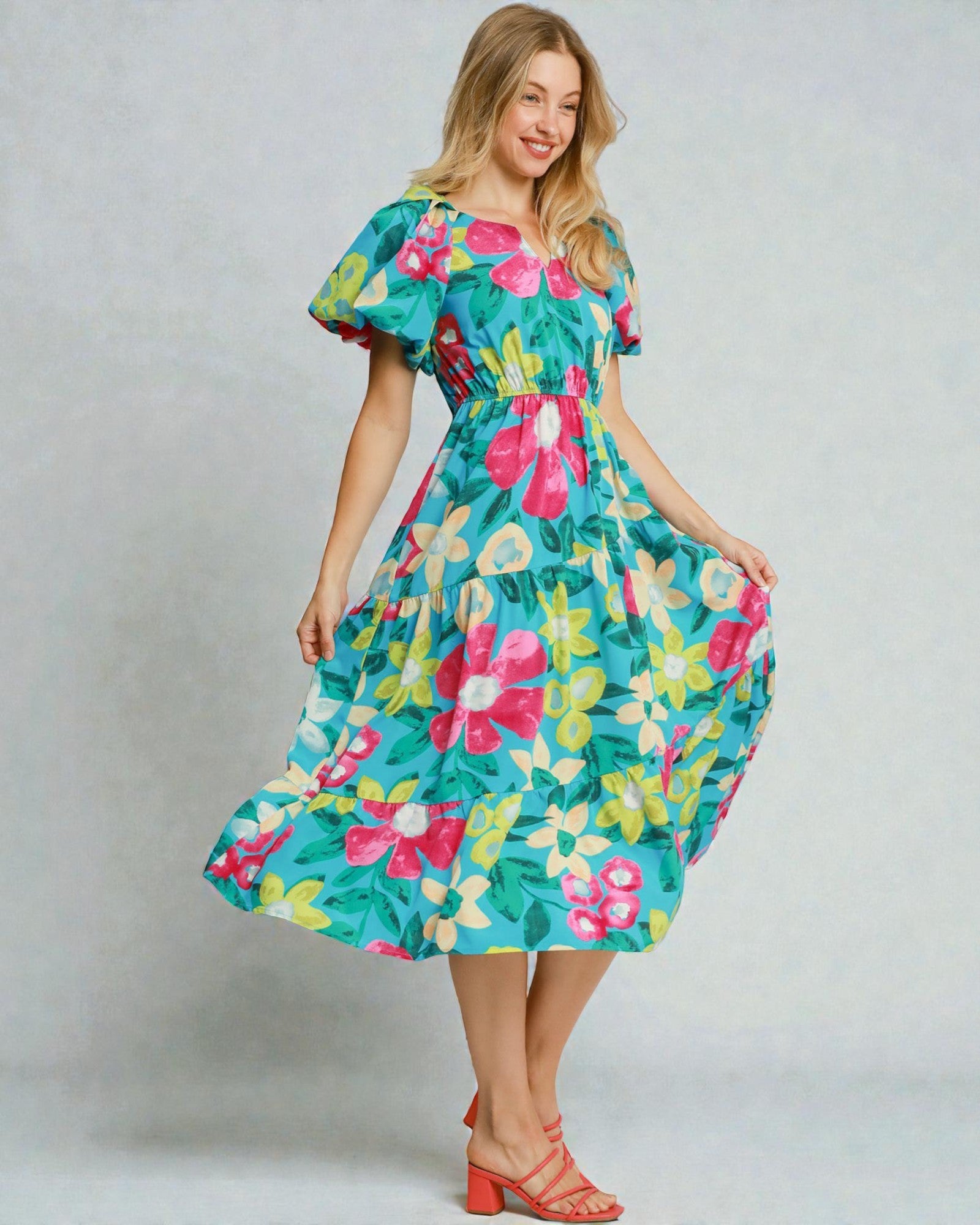 Woman wearing a colorful floral dress against a plain background