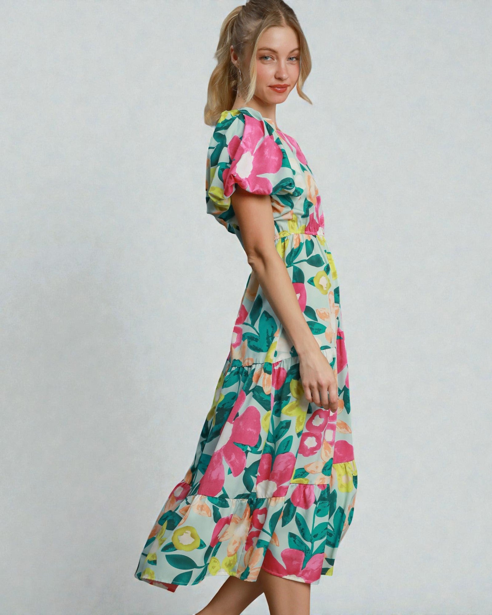 Woman wearing a colorful floral dress on a plain background