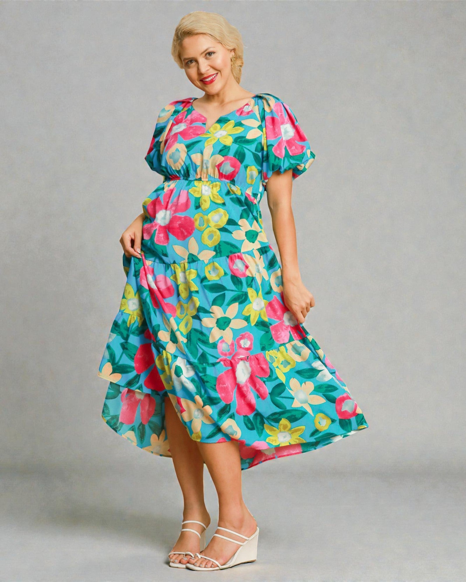 Woman wearing a colorful floral dress against a gray background