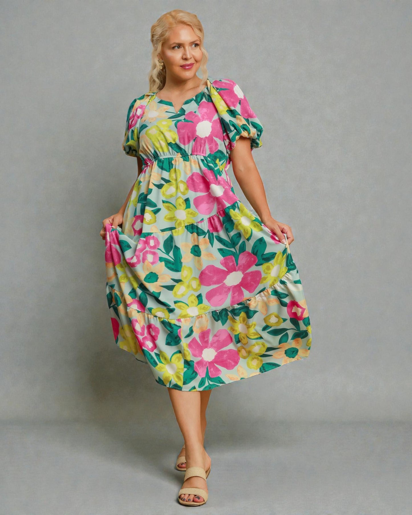 Woman wearing a colorful floral dress against a gray background