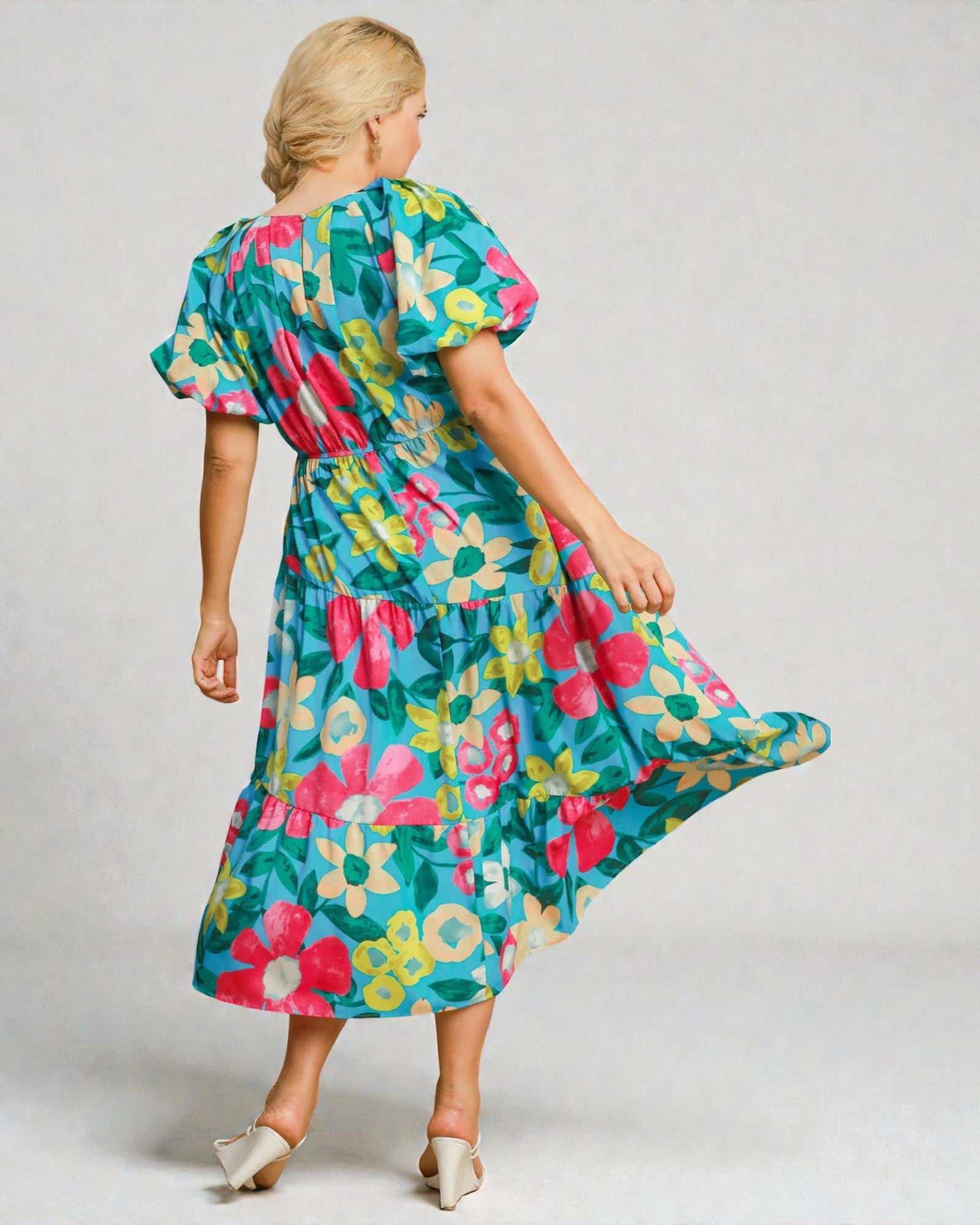 Woman wearing a colorful floral dress on a plain background